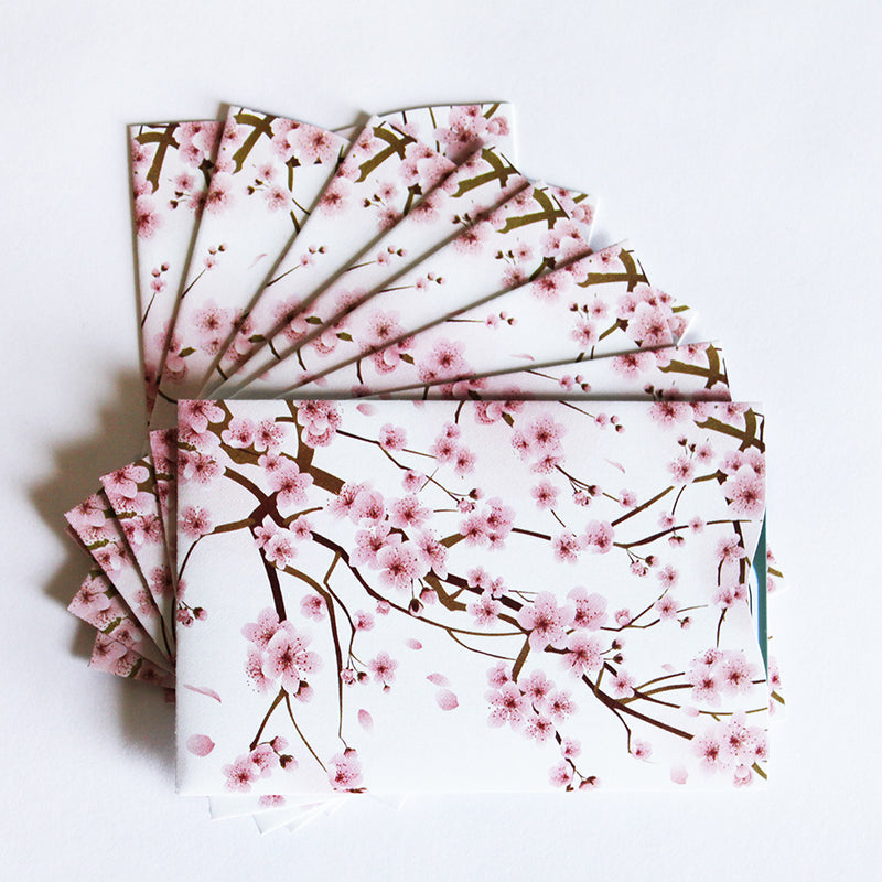A set of sakura blossom note cards on a white surface with Tradevia' RFID Blocking Package of Credit Card Sleeves.