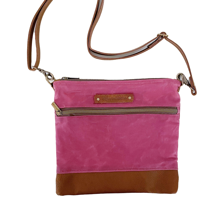A pink and waxed canvas Ellis River Crossbody Bag by Tradevia on a white surface.