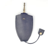 A key partially inserted in a Rogue Leather Key Protective Case by Tradevia, featuring a black textured durable cowhide with a snap button and dangling flap.