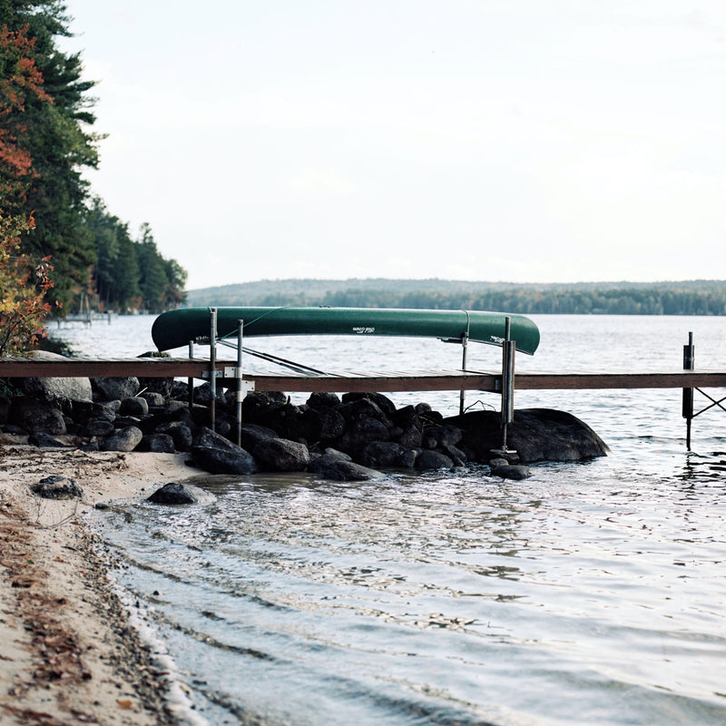 A canoe sits on a dock next to a body of water.