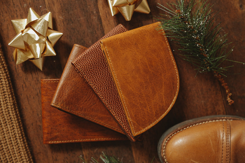 A pair of brown leather wallets and a pair of boots on a wooden table.