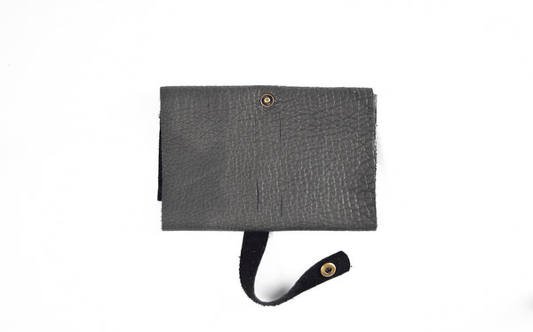 The LEATHER TECH ORGANIZERS - BLACK BISON by Tradevia is elegantly displayed against a white background, featuring bison leather with a strap and snap button closure.