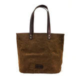 A durable Tradevia Waxed Canvas Tote Bag featuring dark top-grain leather straps and rivet details at the base of the handles.