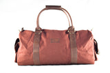 The White Cap Waxed Canvas Duffle from Tradevia, crafted from brown waxed canvas and leather, features two handles and a shoulder strap, set against a plain white background.