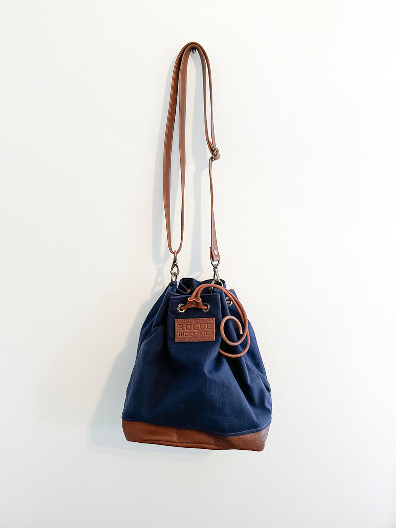 A Made-to-Order Tradevia Kennebunkport Bucket Bag hanging on a wall.