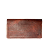 A brown Tradevia leather checkbook cover on a white background, crafted in a Maine workshop.