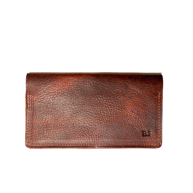 A brown Tradevia leather checkbook cover on a white background, crafted in a Maine workshop.