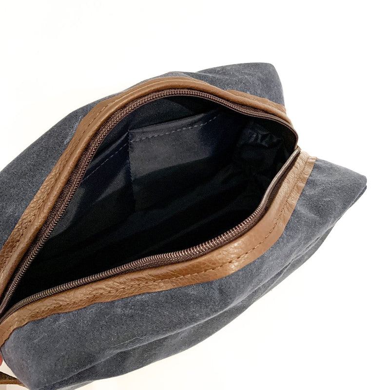A durable, blue and tan Tradevia Waxed Canvas Dopp Kit on a white surface, Made in USA.