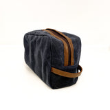 A durable, blue and tan Tradevia Waxed Canvas Dopp Kit made in USA on a white surface.