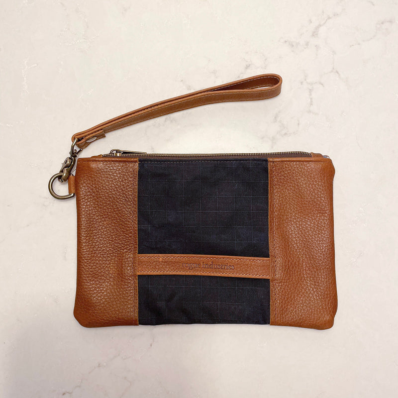 A tan and blue Eastport Clutch waxed canvas zippered pouch with a leather strap from Tradevia.
