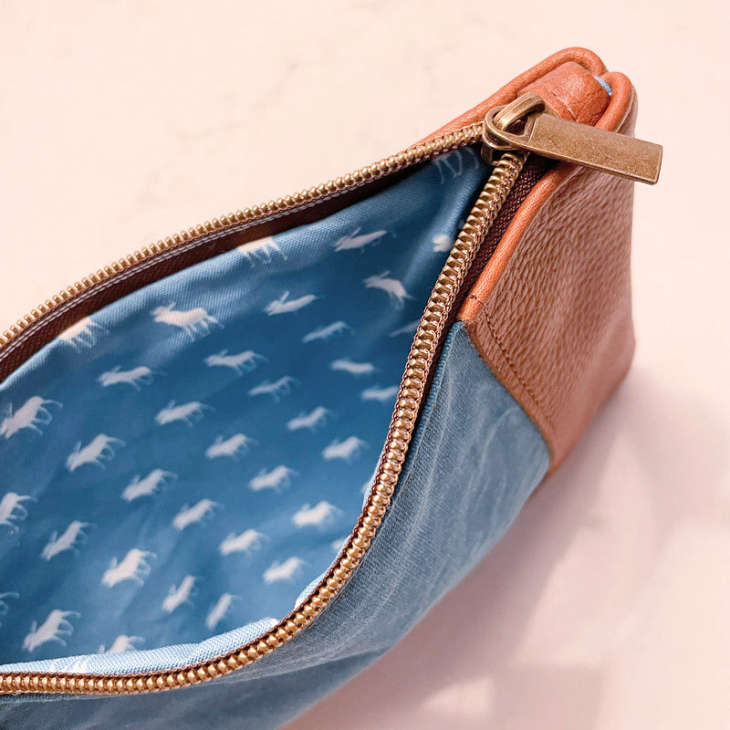 A blue and tan leather Eastport Clutch by Tradevia on a white surface.