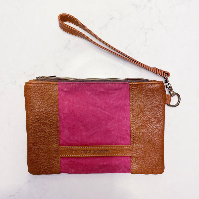 A tan and pink Tradevia Eastport Clutch with a strap.