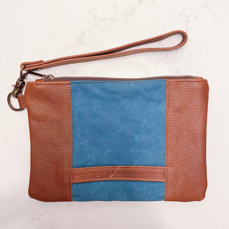 A blue and tan waxed canvas and leather Eastport Clutch wristlet by Tradevia.