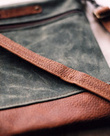 A green and brown waxed canvas and cowhide Tradevia Ellis River Crossbody Bag.