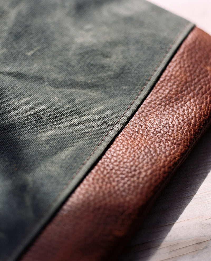 A close up of a green and brown cowhide leather Tradevia Ellis River Crossbody Bag.