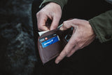 A man is holding a Tradevia NFL leather front pocket wallet with an RFID-blocking credit card in it.