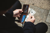A man holding a Heritage Wallet from Tradevia made of genuine cowhide leather with money in it.