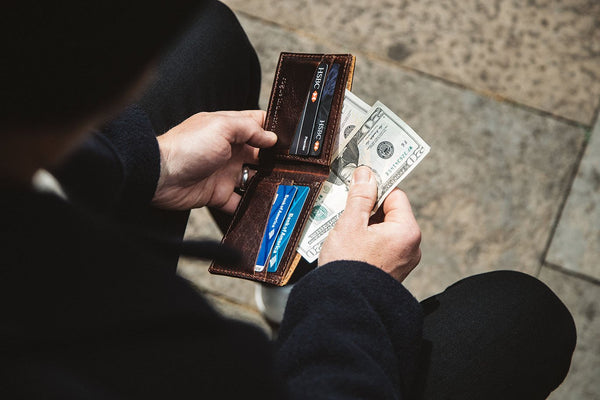 A man holding a Heritage Wallet from Tradevia made of genuine cowhide leather with money in it.