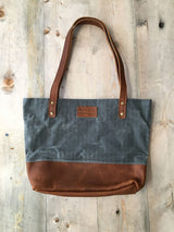 A Saco River Tote Bag by Tradevia on a wood surface.