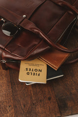 A Katahdin leather briefcase by Tradevia sitting on top of a wooden table.