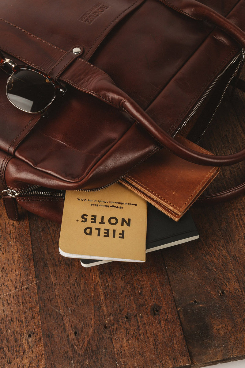 A Katahdin leather briefcase by Tradevia sitting on top of a wooden table.