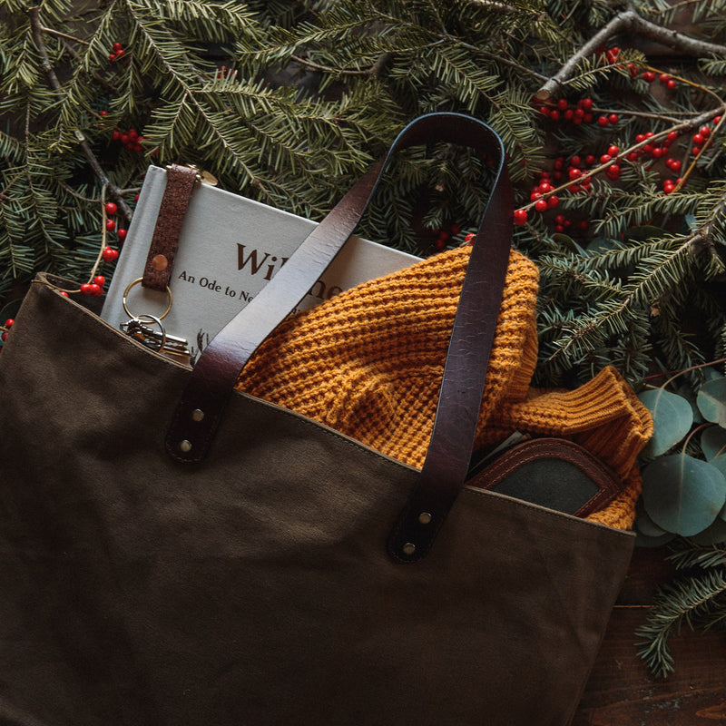 A durable, brown Tradevia waxed canvas tote bag with top-grain leather straps.