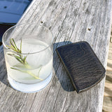 A Tradevia Minimalist Wallet and a drink on a wood surface.