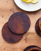 A set of Tradevia' Moose Leather Coaster Set on a wooden table.