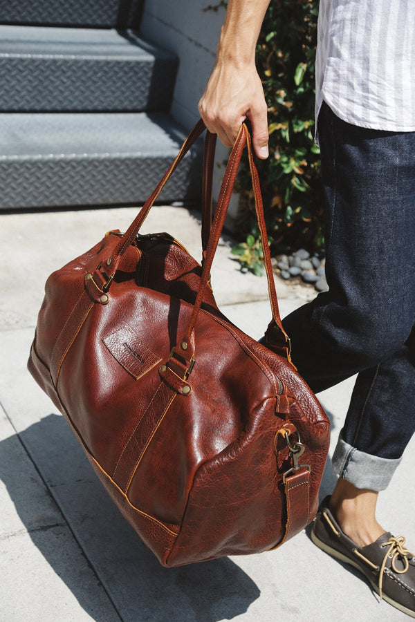 A person carrying a Tradevia Mount Blue Leather Duffle made of premium top grain leather.