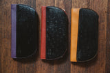A group of Tradevia RFID Blocking Clutch - Ostrich Print cases on a wood surface.
