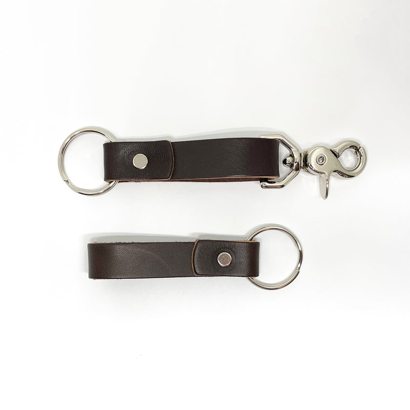 Two durable Tradevia brown leather keychains on a white background.