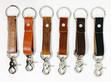 A row of different colored, durable Tradevia leather keychains on a white background.