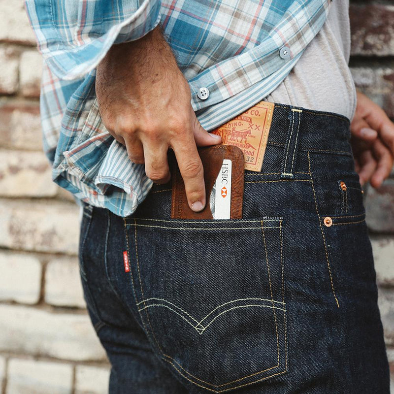 A man is holding a Tradevia Bison Card Case in his jeans pocket.