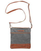 A grey waxed canvas Ellis River Crossbody Bag with brown cowhide straps by Tradevia.