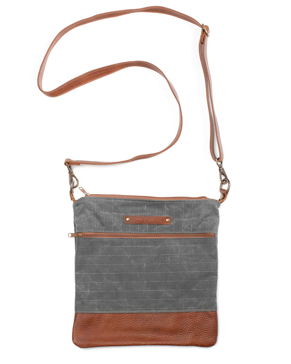 A grey waxed canvas Ellis River Crossbody Bag with brown cowhide straps by Tradevia.