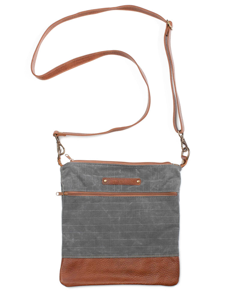 A grey waxed canvas Ellis River Crossbody Bag with brown cowhide straps by Tradevia.