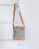 A small Ellis River Crossbody Bag by Tradevia hanging on a ladder.
