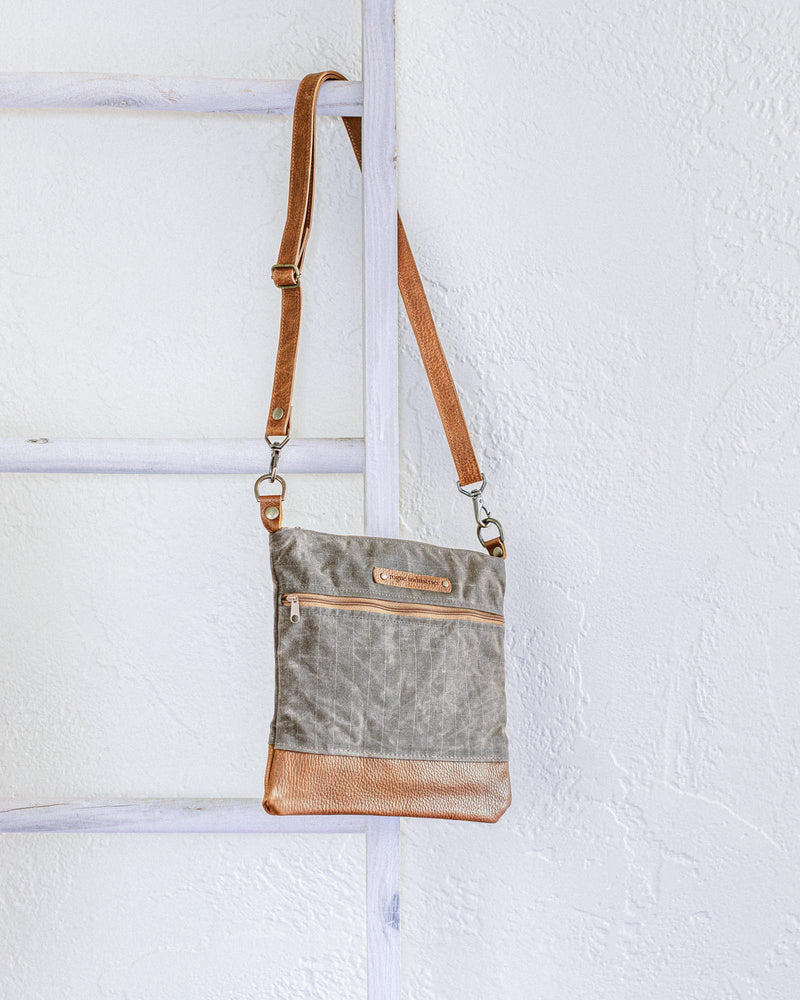 A small Ellis River Crossbody Bag by Tradevia hanging on a ladder.