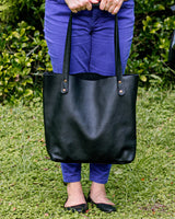 A person holding a black Tradevia Fore Street Tote Bag.