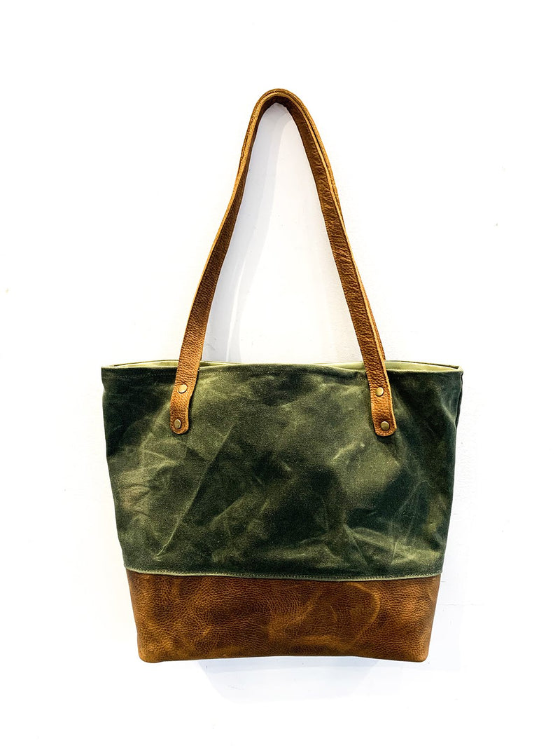 A green and waxed canvas Saco River Tote Bag with tan leather accents by Tradevia.