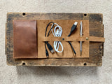 A Tradevia top-grain leather tech organizer with cables, a pen, and a pencil inside.