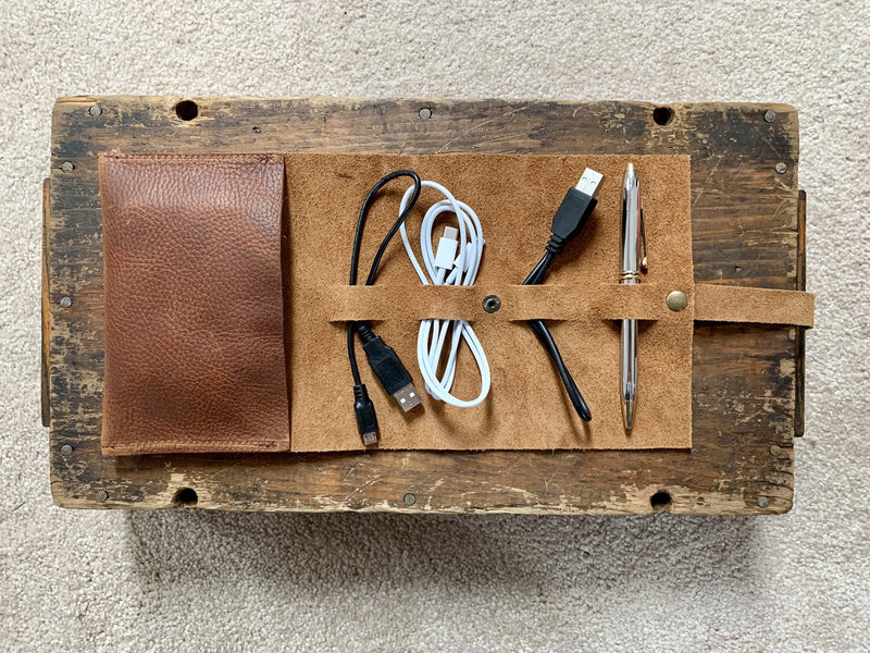 A Tradevia top-grain leather tech organizer with cables, a pen, and a pencil inside.