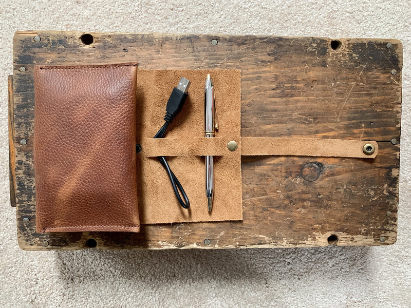 A pen case and pencils on a wood surface, next to a top-grain leather Tradevia Leather Tech Organizer.