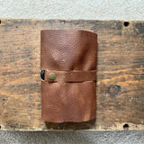A top-grain leather Tradevia Leather Tech Organizer on top of a wooden box.