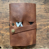A brown Tradevia Leather Tech Organizer with cables attached to it.