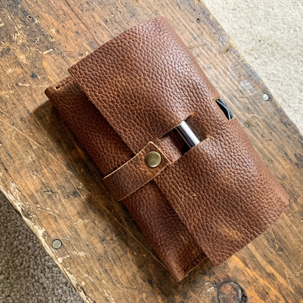 A brown Tradevia Leather Tech Organizer sitting on top of a wooden table.