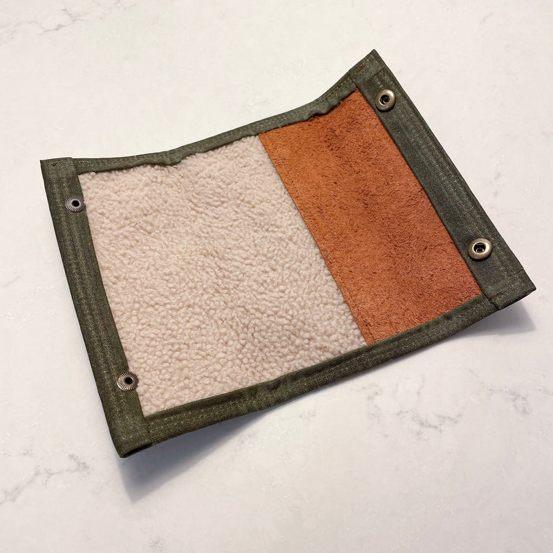 A Tradevia Rogue River Fly Fishing Wallet in green and tan waxed canvas on a white surface.