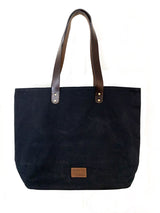 A durable, black Tradevia waxed canvas tote bag with top-grain leather straps.