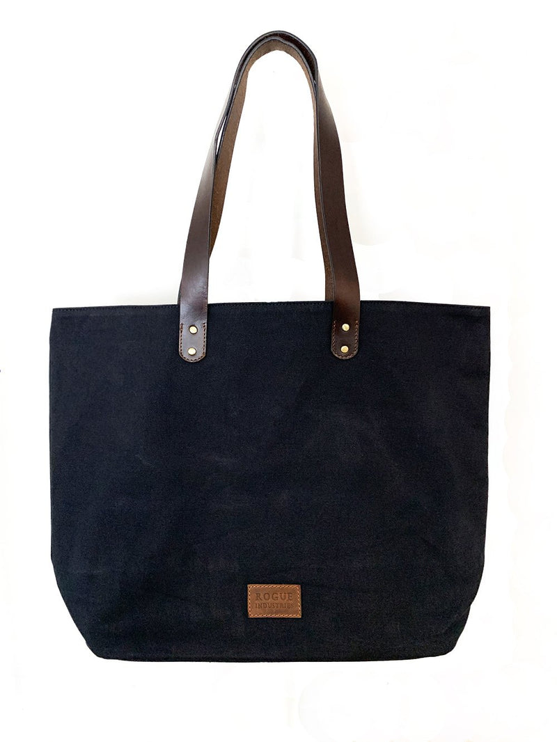 A durable, black Tradevia waxed canvas tote bag with top-grain leather straps.
