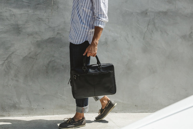 A man walking with a black, genuine leather West End Slim Laptop Bag by Tradevia.